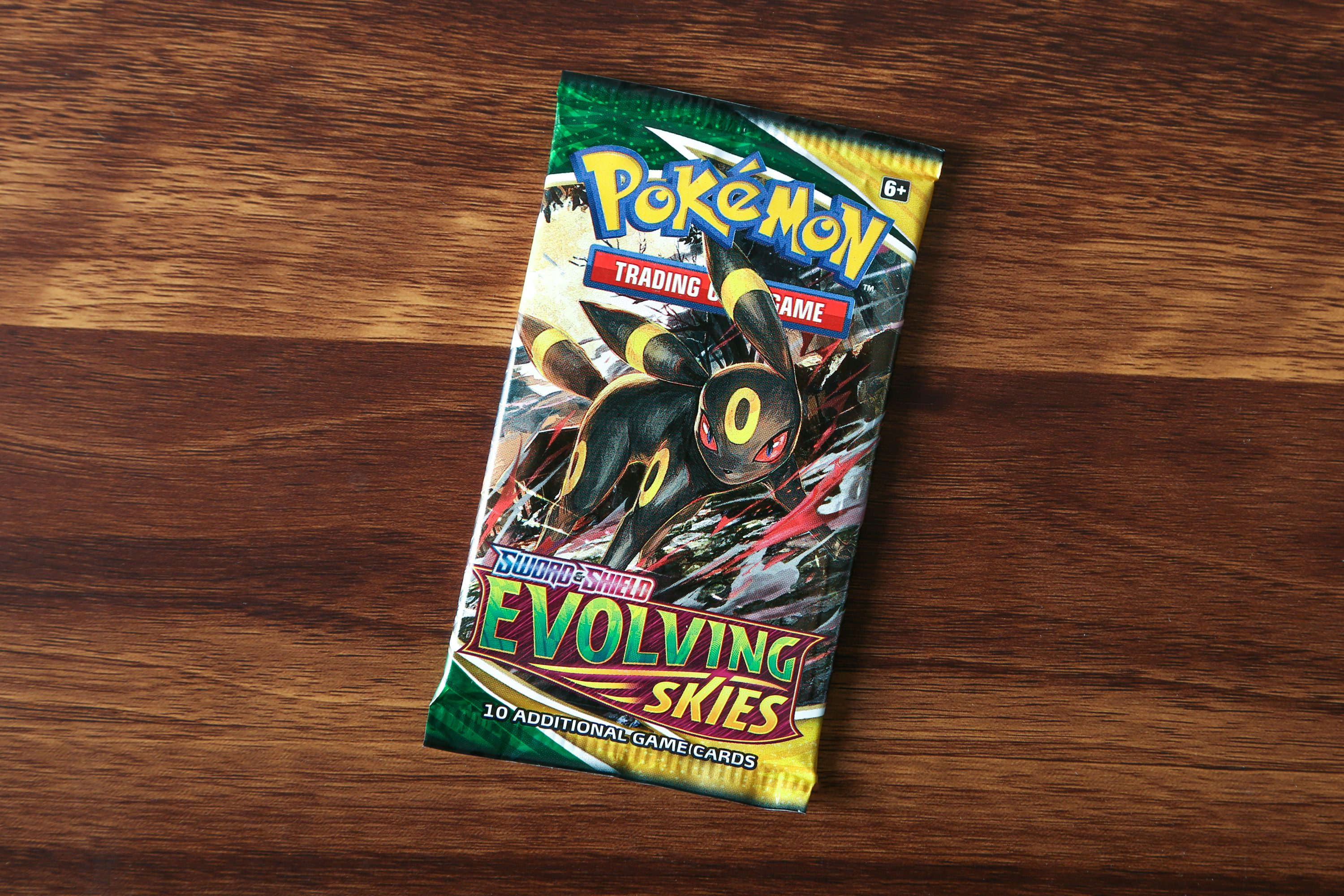 Paquet de cartes Pokémon Trading Card game Évolving Skies posé sur une surface en bois, featuring Umbreon Pokémon et texte coloré.
