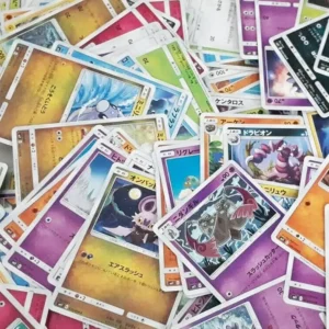 Carte à collectionner jouée en tas, featuring des Pokémon et autres TCG japonais avec des cadres colorés et textes japonais.